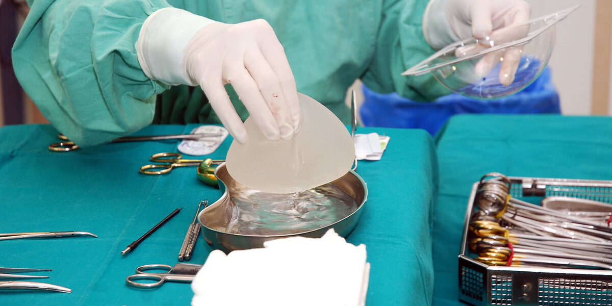 Breast Implants Featured image showing surgeon grabbing silicone breast implant during surgery