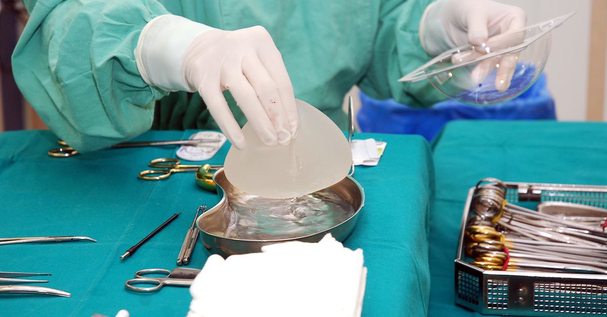 Breast Implants Featured image showing surgeon grabbing silicone breast implant during surgery