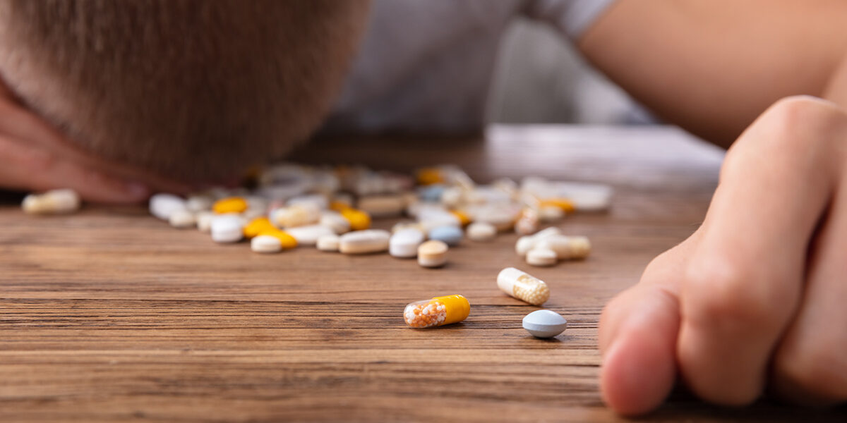 Opioid Crisis Almost Hit Germany man with his head down on table with pills spilled out of their respective bottles