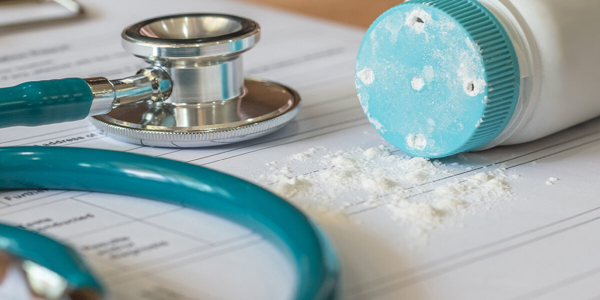 Talc Powder Cancer Lawsuit article featured image showing talcum powder bottle on top of paperwork next to stethoscope