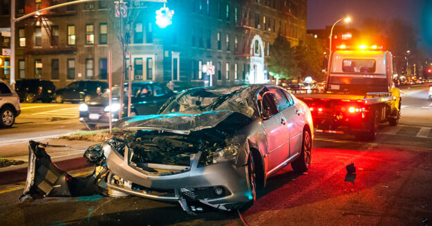 Car Accident during COVID-19 with smashed front-end and police car behind it with lights on