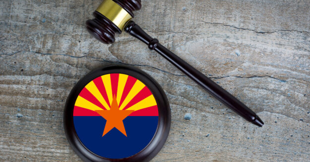 Arizona Human Trafficking Undercover Sting Results in 34 Arrests gavel laid next to round block with Arizona state flag printed on it