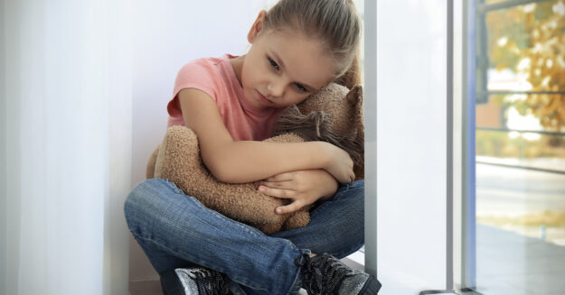Child Sexual Abuse Statute of Limitations in Arizona sad little girl holding teddy bear in her arms on a window sill