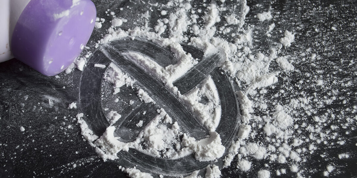 Johnson & Johnson Ordered to Pay $120M in Talcum Powder Lawsuit big letter X created out of powder with purple bottle tipped over