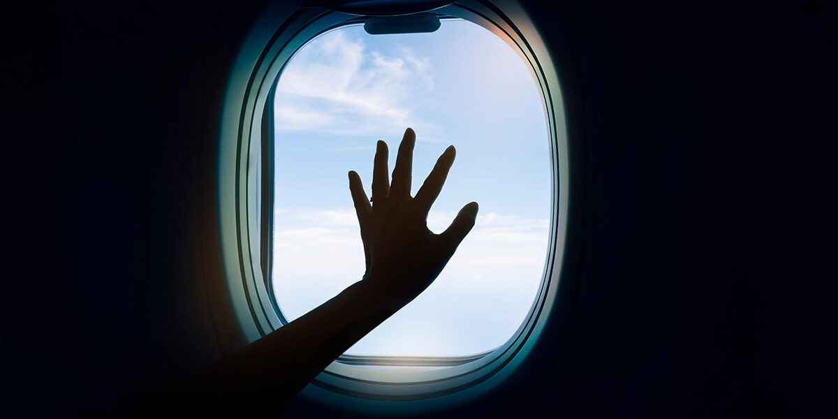 Sexually Assaulted On A Plane You Have Rights hand against the dark pane of a window on an airplane
