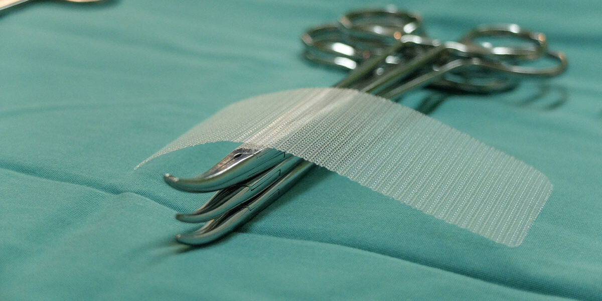 Ventralex Hernia Mesh Trial Ends with $250K Verdict - example of mesh sitting upon a few sets of forceps on light green cloth in surgery room
