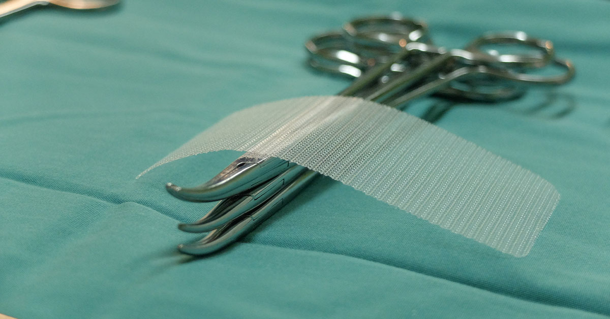 Ventralex Hernia Mesh Trial Ends with $250K Verdict - example of mesh sitting upon a few sets of forceps on light green cloth in surgery room