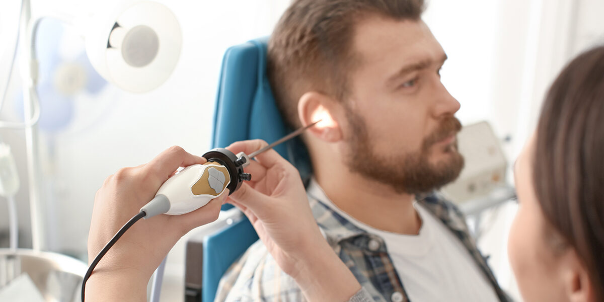 Tepezza and its associated hearing damage risks ear doctor using a tool to examine inside of mans ear